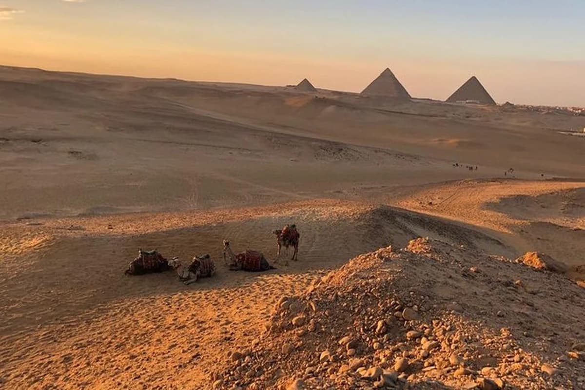 A desert track running toward dunes under a wide Egyptian sky.