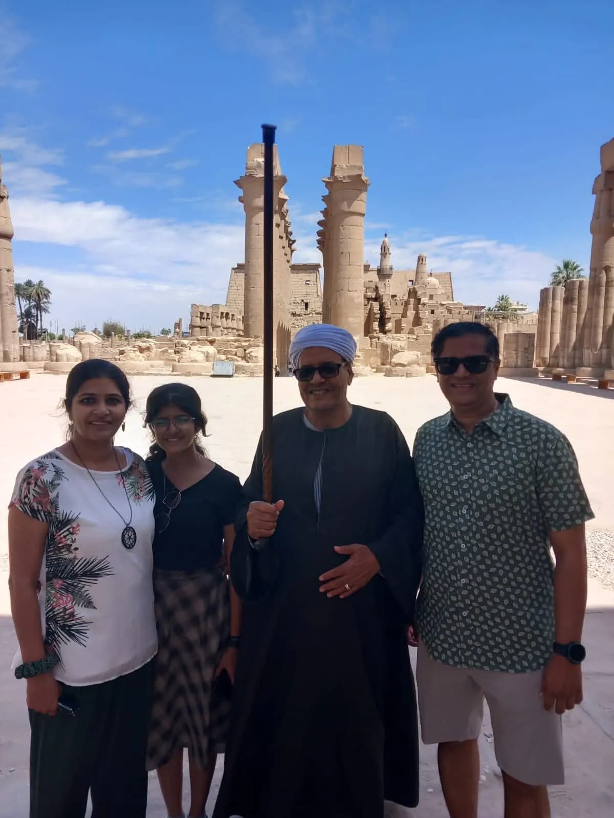 A family posing with their Egyptian guide in front of Luxor Temple