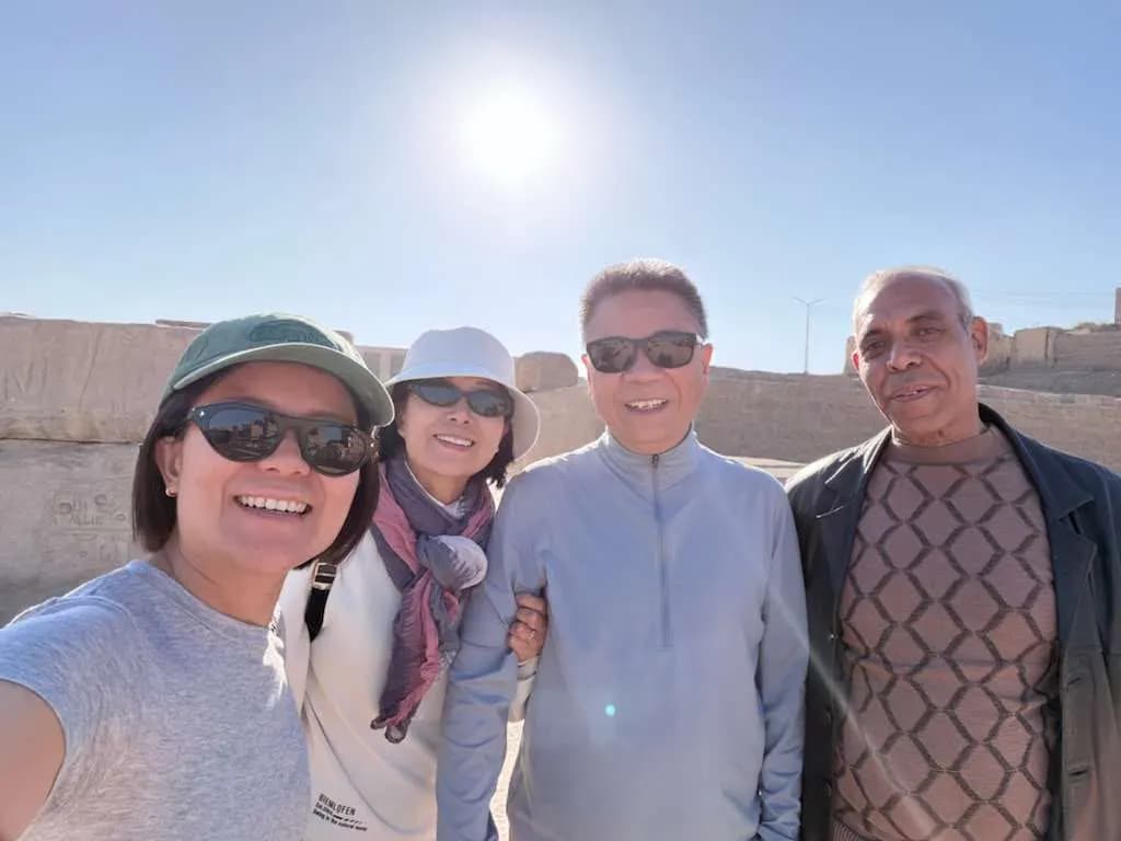 Four travelers smiling for a sunny selfie at a Luxor temple