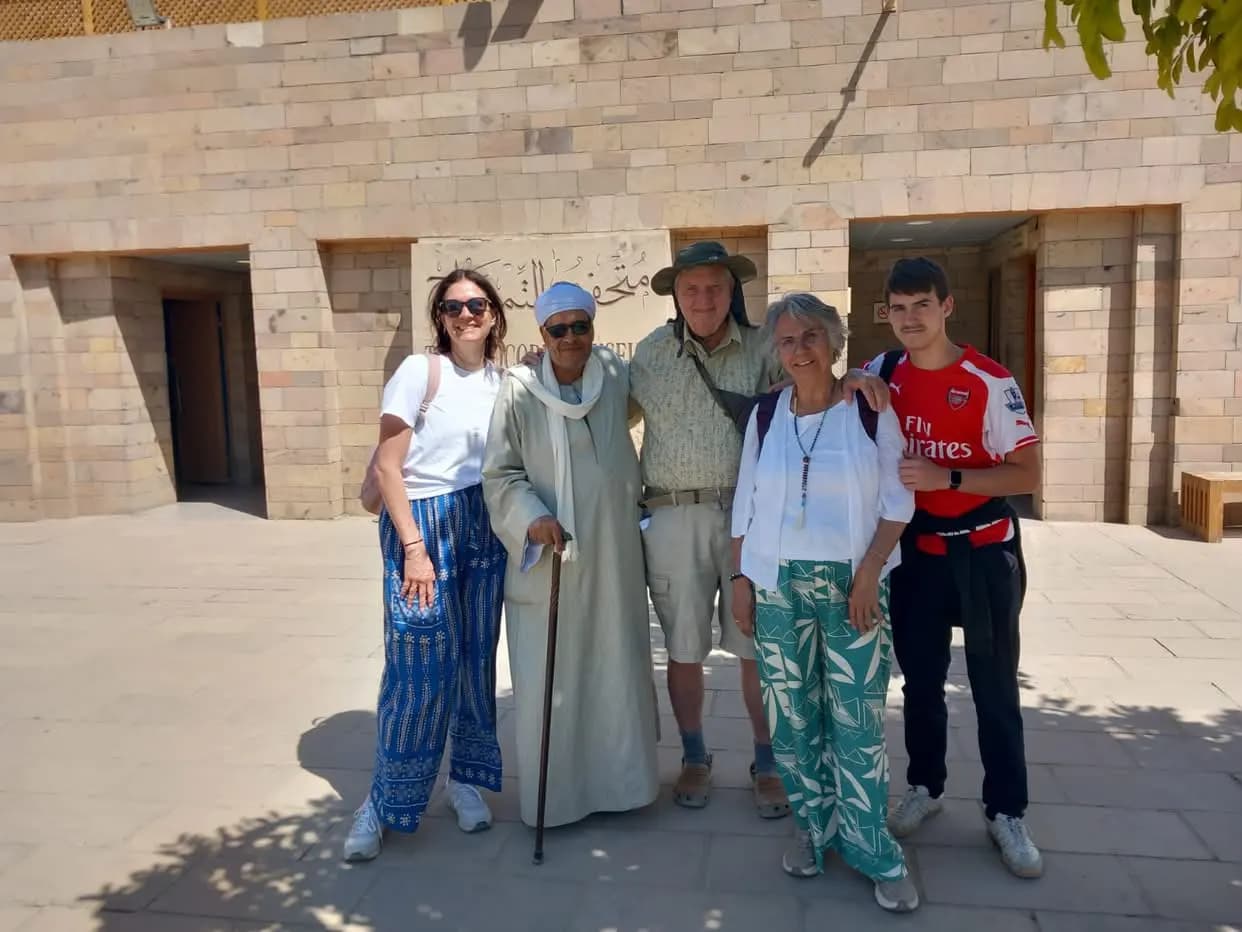 Travelers posing with their Egyptian guide outside a museum entrance