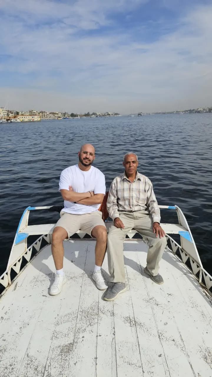Two travelers seated on the bow of a traditional boat on the Nile