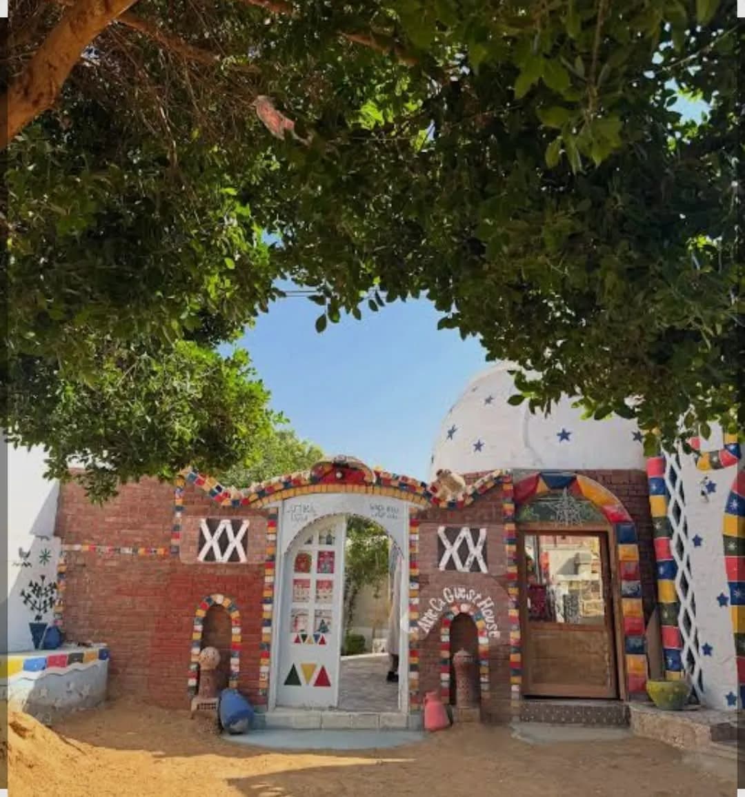A decorated Nubian-style guest house entrance framed by a leafy tree