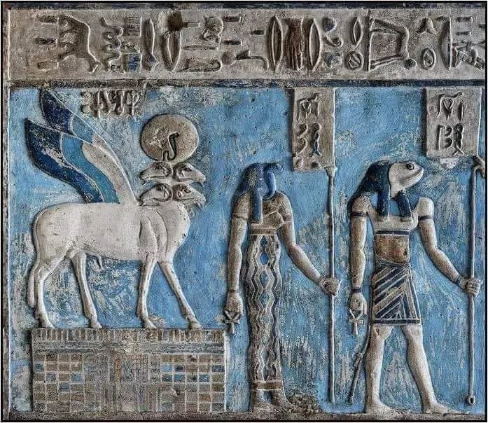 A painted blue relief of a winged creature and two deities in an ancient temple